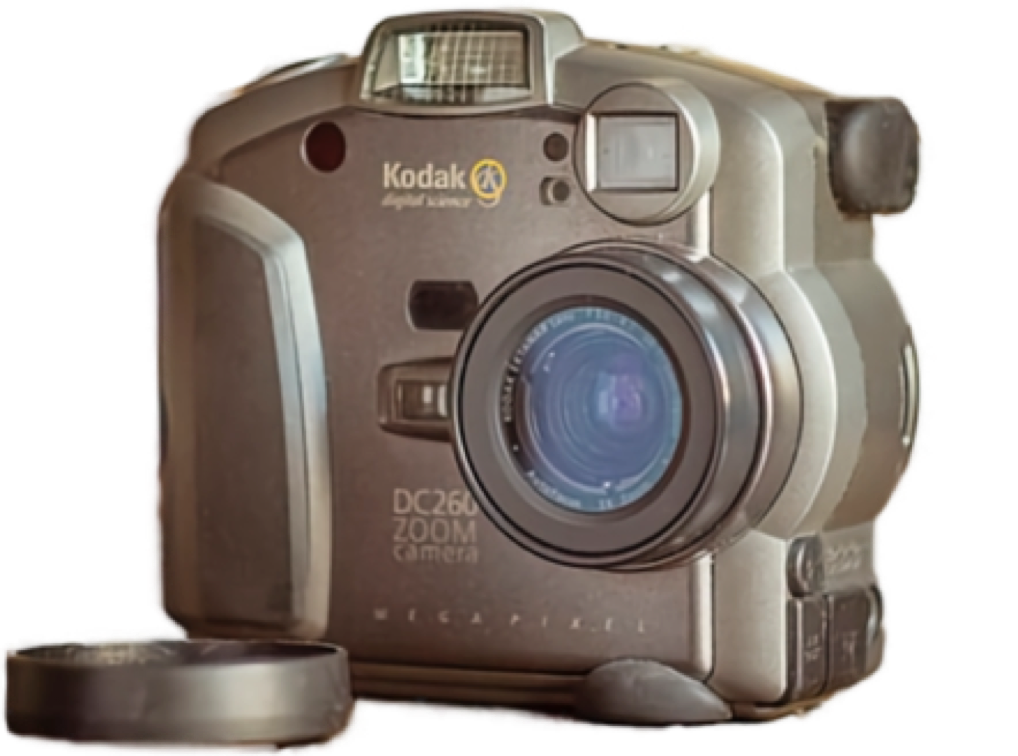 A Kodak digital camera with a lens cap placed beside it.