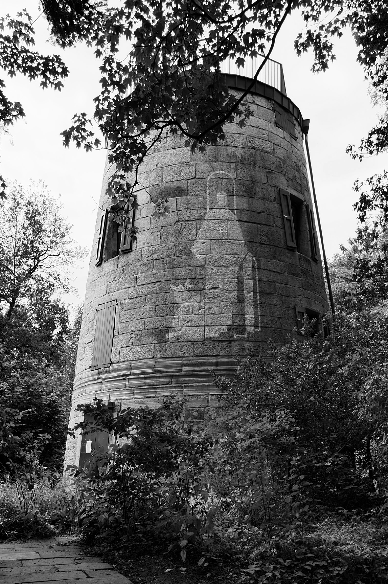 A black and white image of an ornate wooden pulpit with a staircase, situated in a church  with a large window.