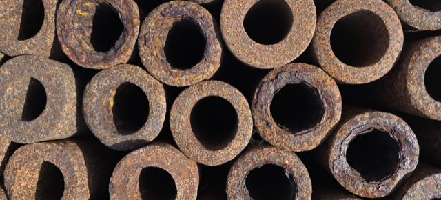 A close-up view of stacked rusty metal pipes with visible circular openings.
