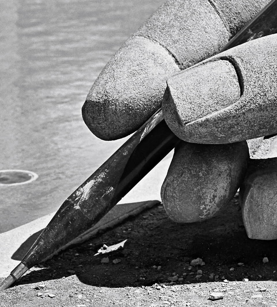 A large hand holding a pen, drawing on a surface.