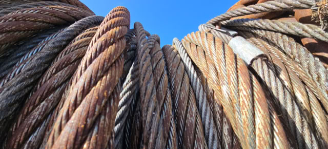Close-up of several large, coiled metal cables against a clear blue sky.