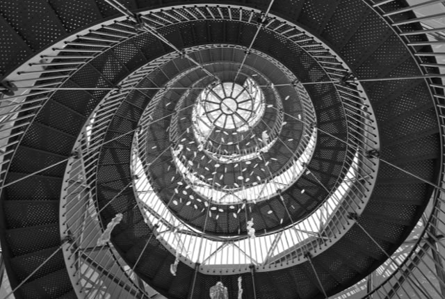 Spiral staircase viewed from below, creating a circular pattern with metal railings and steps.