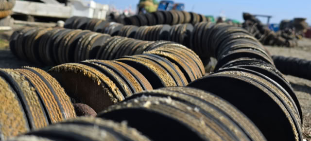 Close-up of a row of rusty, circular metal objects lying on the ground, with a clear blue sky in the background.